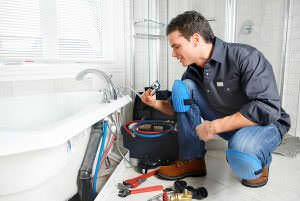 A plumber working on a bath tub faucet