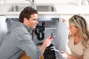 Plumber working on a kitchen sink and talking with an Anaheim Hills homeowner