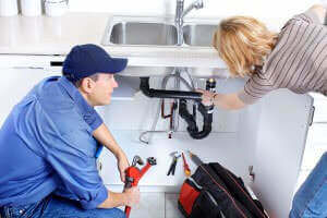 Plumber inspecting a kitchen sink with a Fountain Valley homeowner