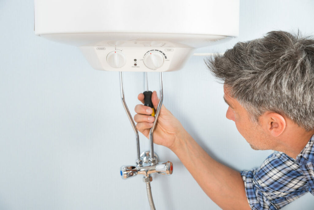A man making adjustments to a water heater