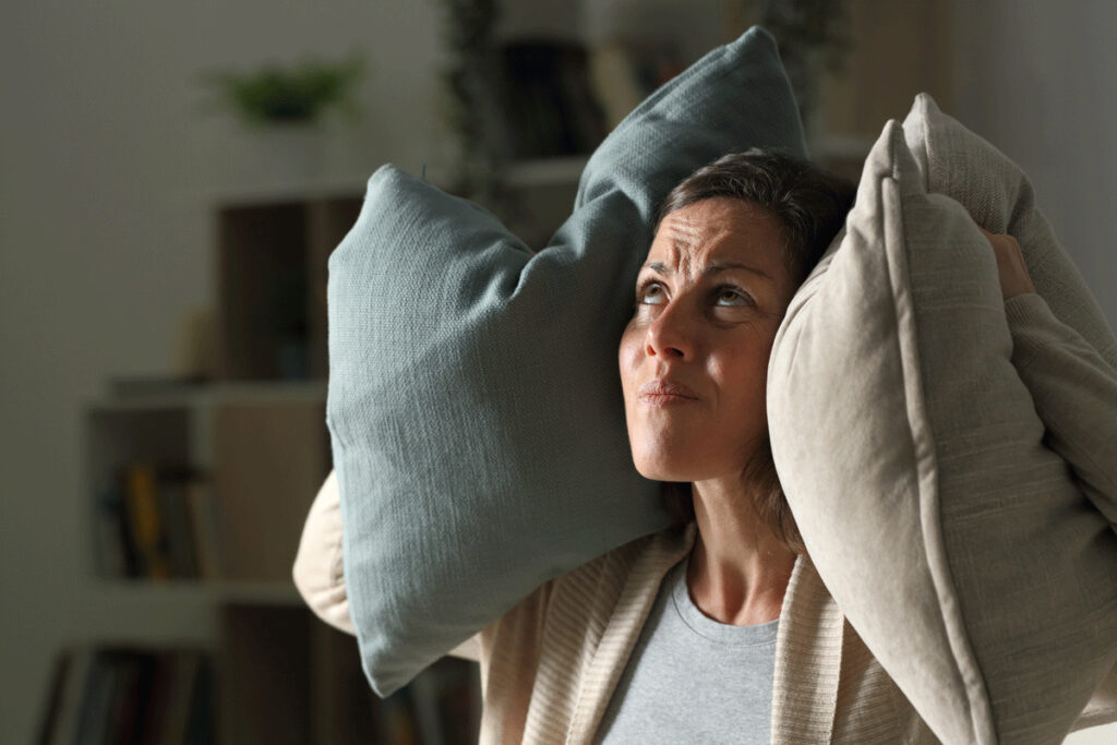 Woman covering ears with pillows because her furnace is loud